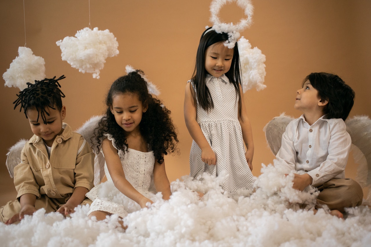 Crianças em trajes de anjo brincando com algodão