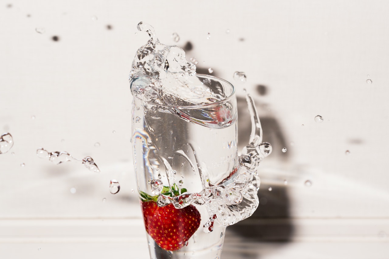 Clear Drinking Glass With Strawberry and Overflowing Water