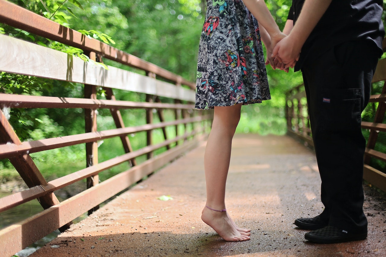 Barefoot Woman And Man Wearing Black Shoes Standing on a Bridge