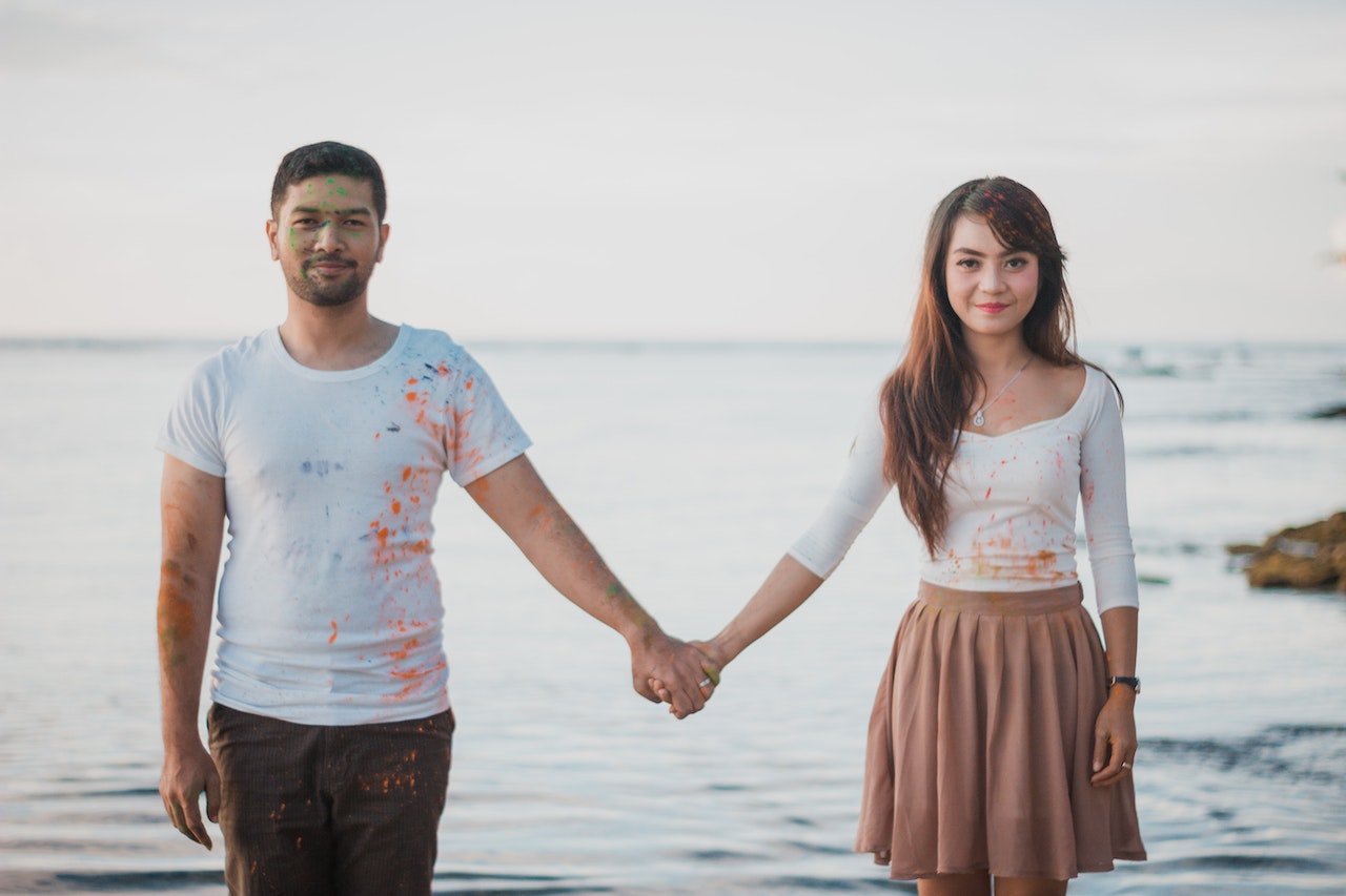 Man and Woman Holding Hands While Standing Beside The Sea