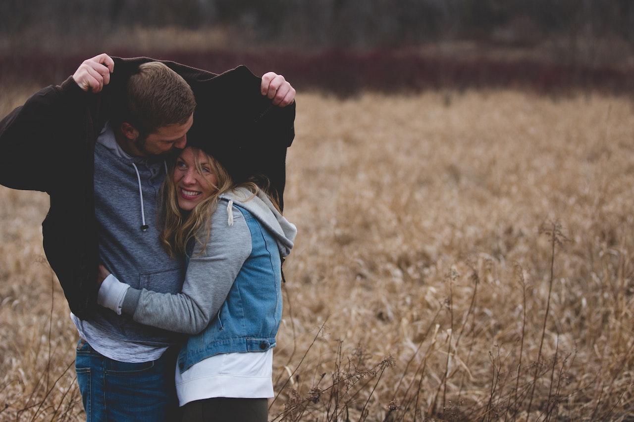 Man and Woman Hugging In The Grass Field