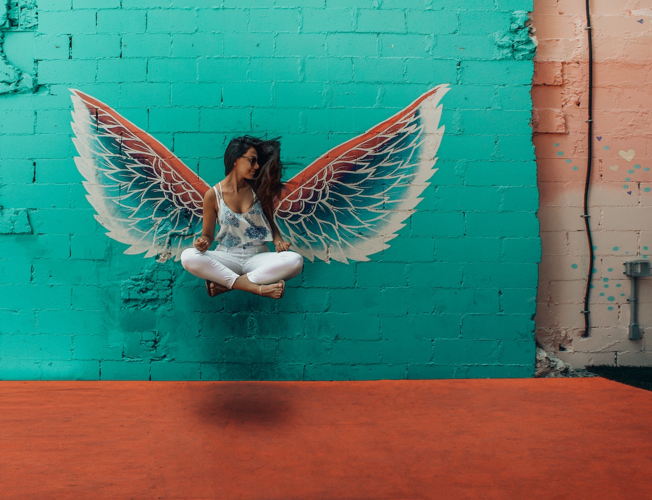 Woman Taking Picture Beside Wings Painting On The Wall