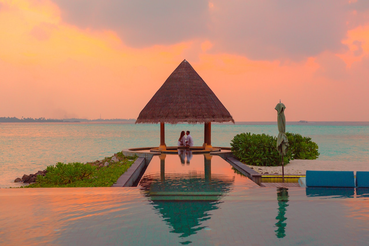 Couple Under A Hut In Between The Sea and Infinity Pool