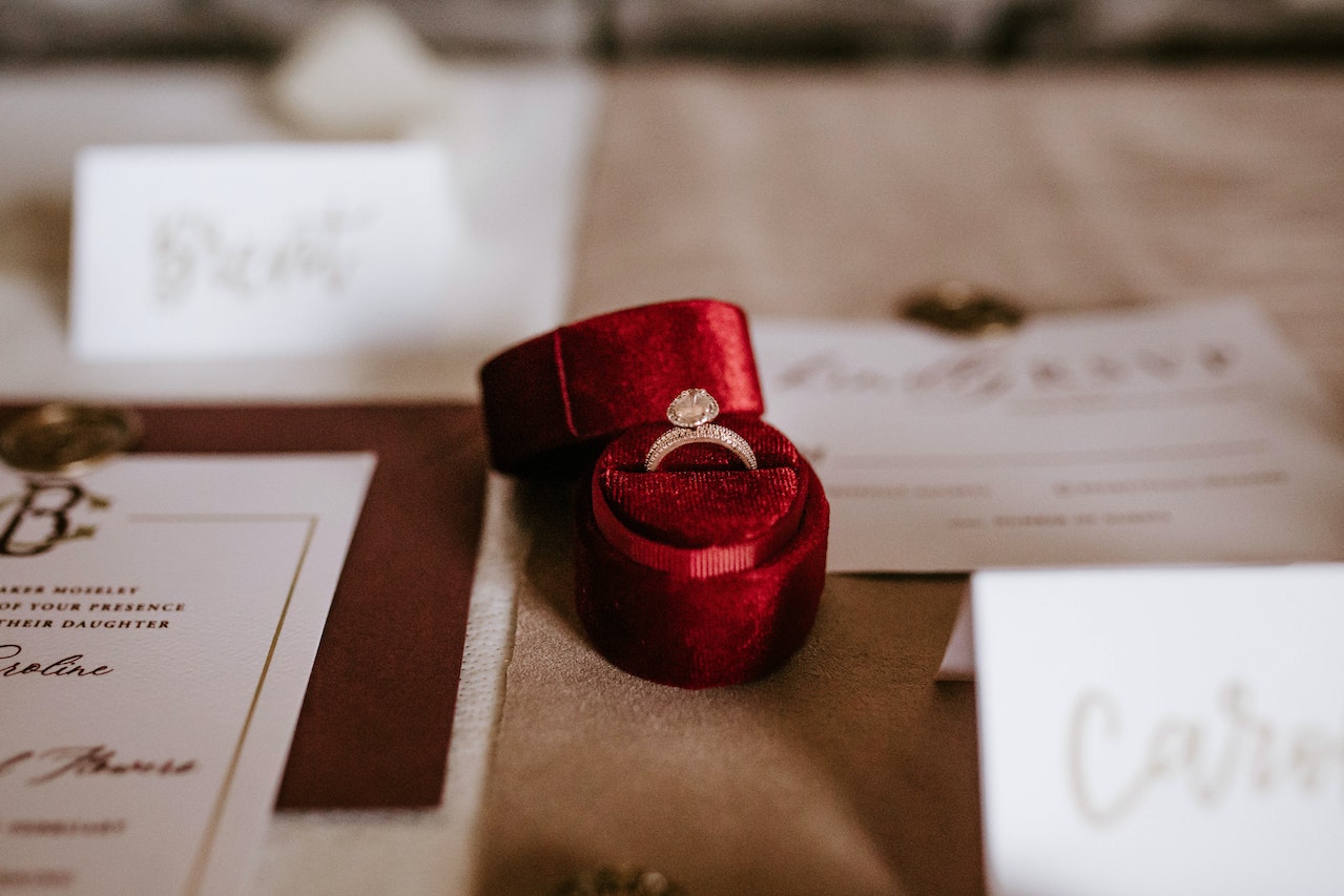 Red Box With Diamond Ring Placed On Table With Invitation Cards