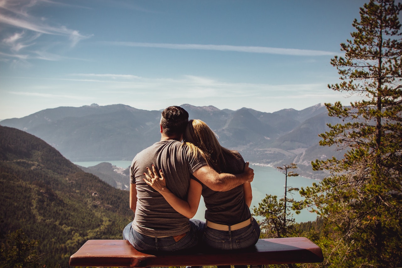 Man and Woman Sitting on the Bench Overlooking The Mountains