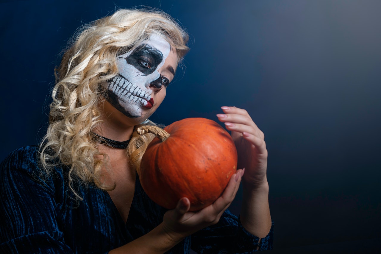 Woman With evil Face Paint holding a Pumpkin