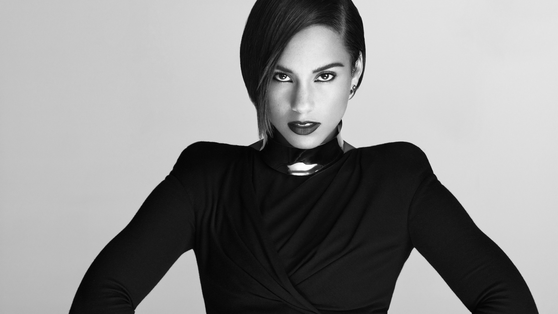 Alicia keys wearing a black dress and standing with her hands on her waist