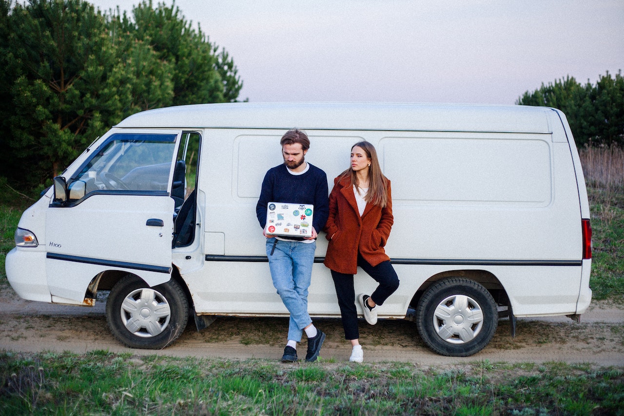 Woman and a man leaning on a White Van