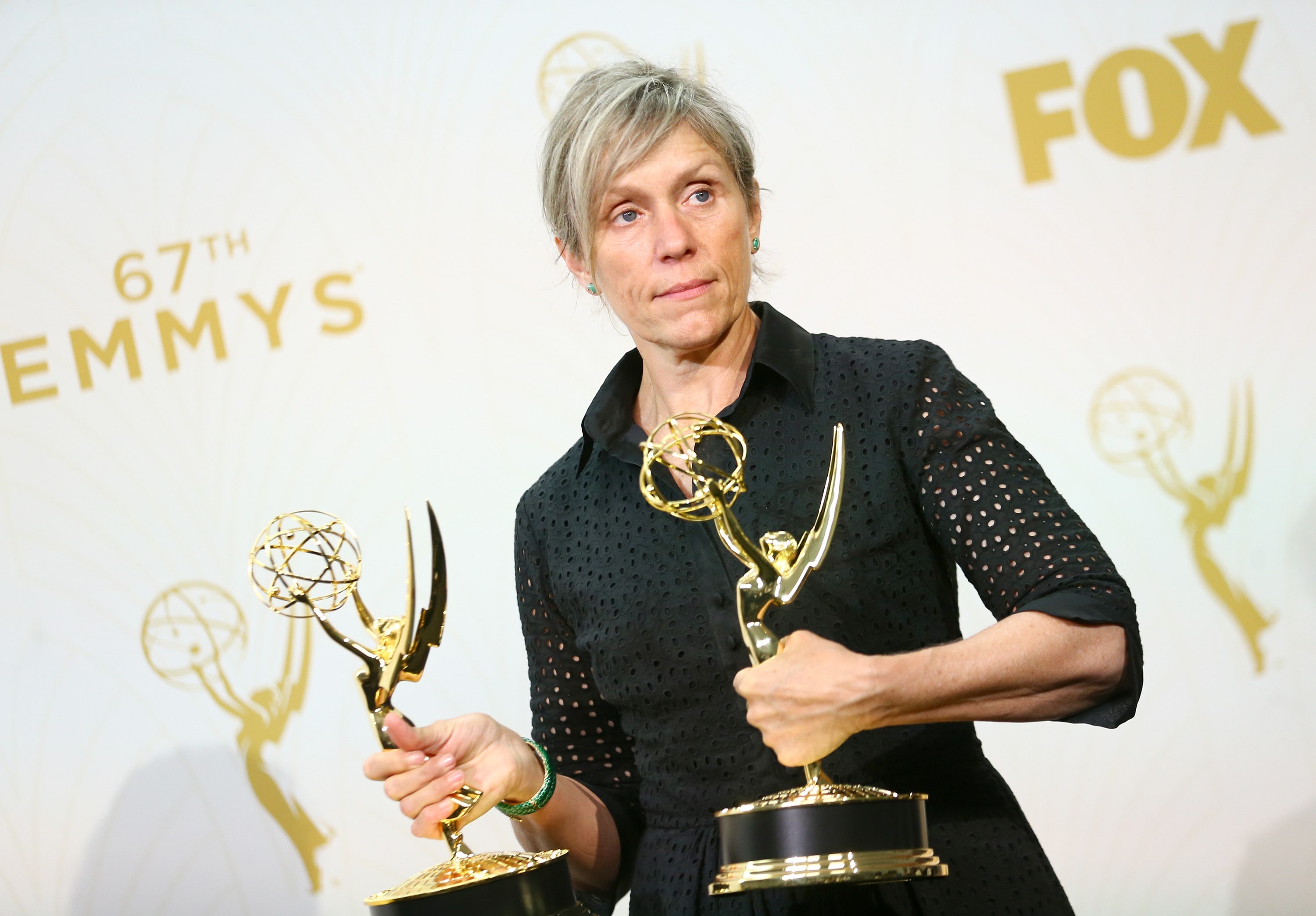 Frances McDormand wearing black dress and holding trophies with her both hands
