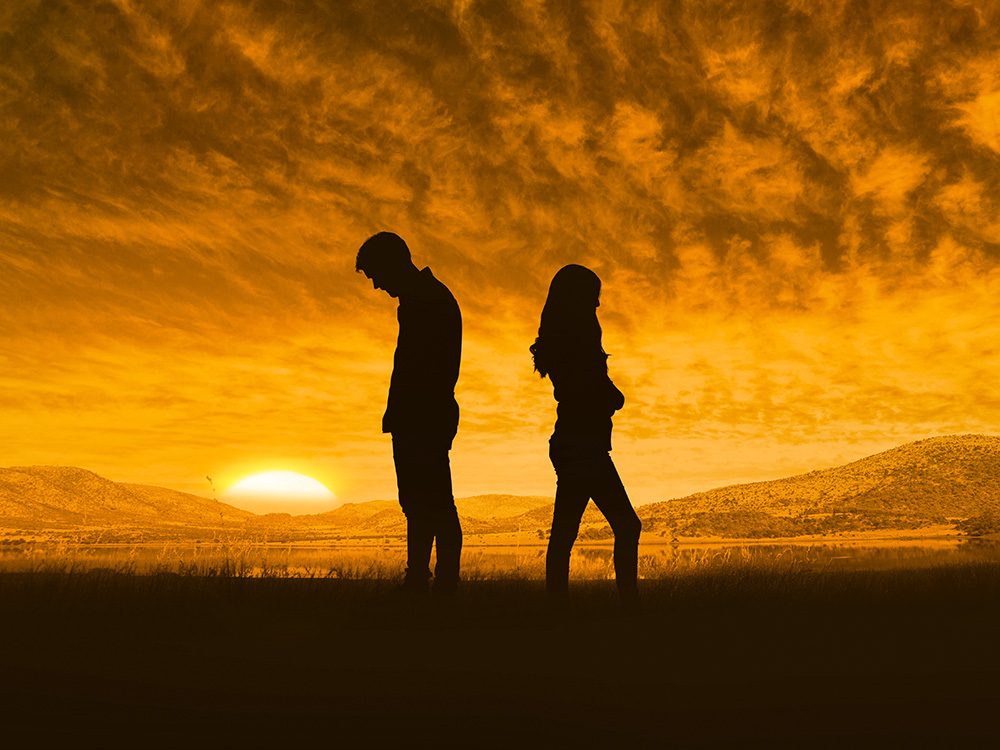 A couple standing and having an argument in front of the sunset