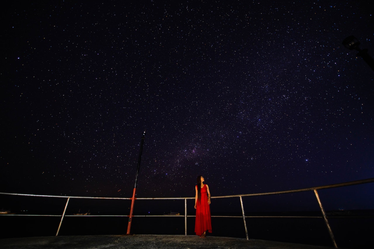 Anonymous woman on viewpoint admiring starry sky at night