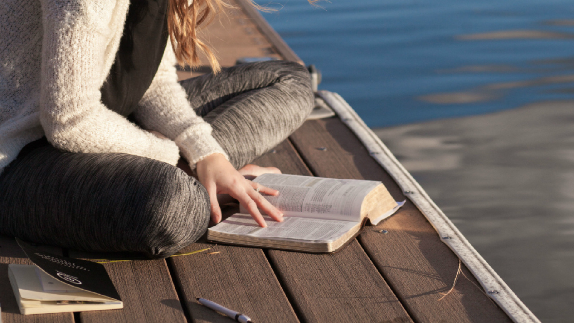 A woman reading a Bible while sitting on a wooden platform