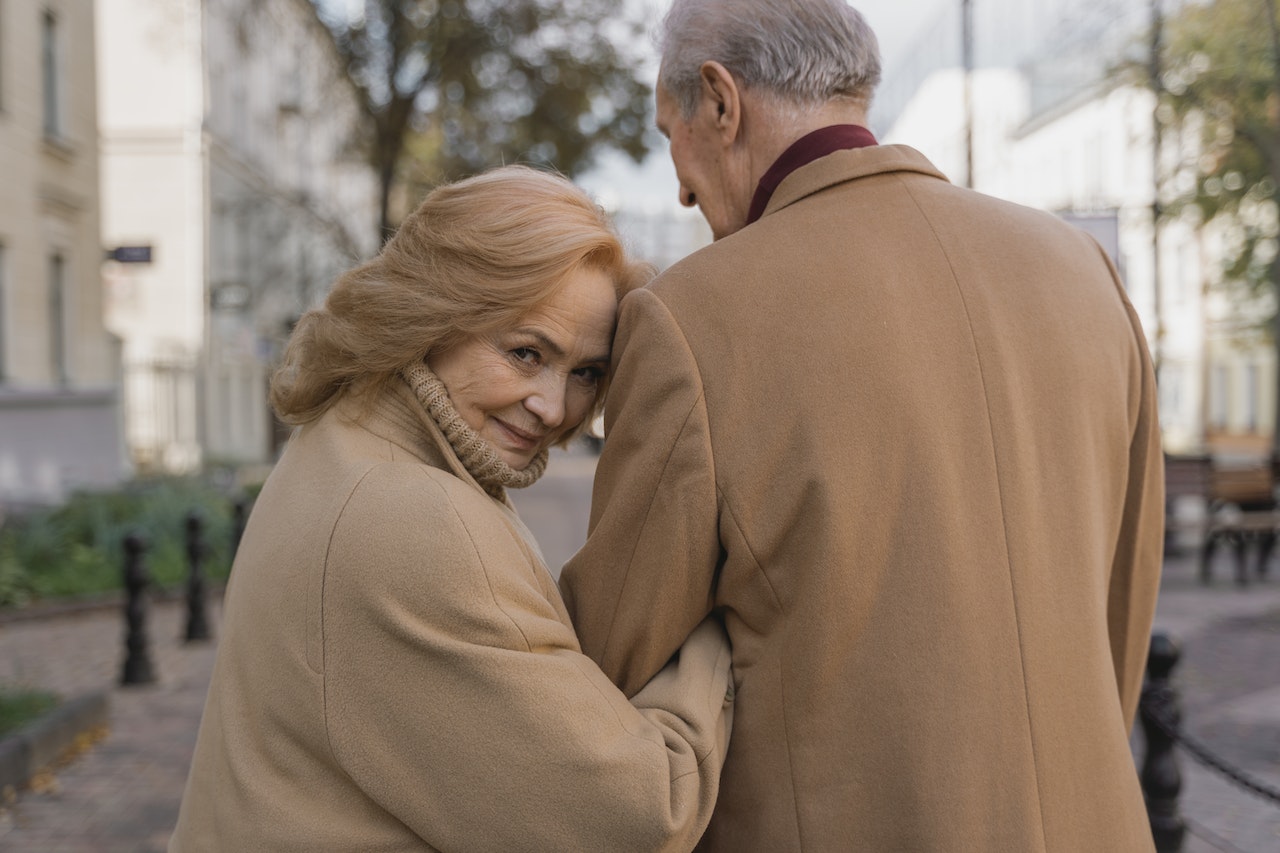 An Old Woman Holding on An Old Man's Arm While Walking