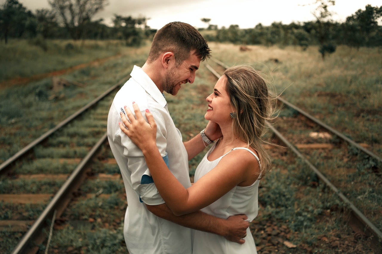 Smiling Man and Woman Facing Each Other In The Middle Of Railway Tracks