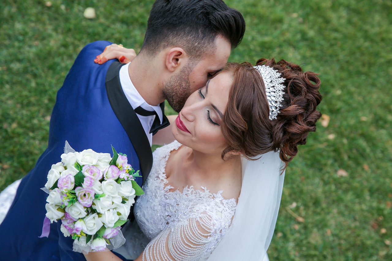 A bride holding her bouquet while the groom kisses her cheek