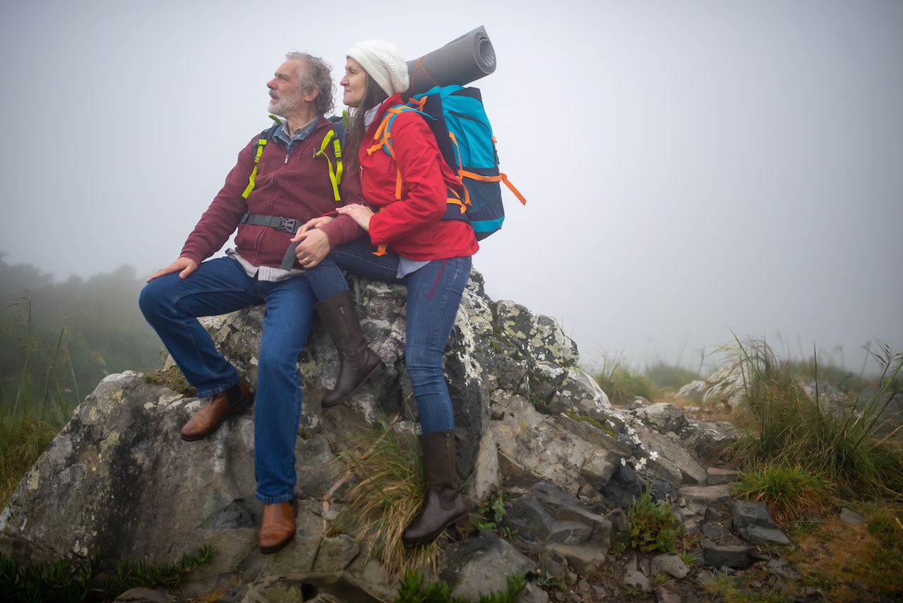 Couple in Backpacks Sitting on Gray Rock Formation