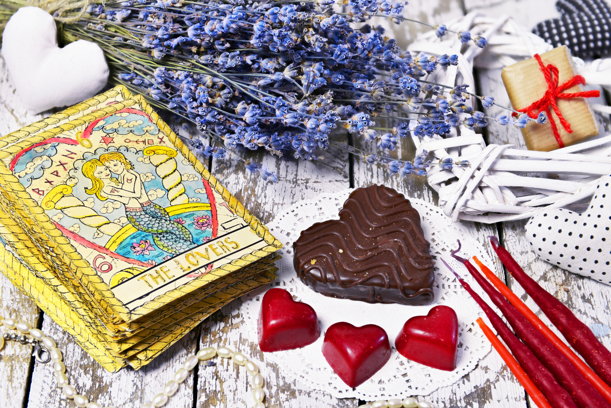 A deck of love tarot cards with heart shaped chocolates and red candles