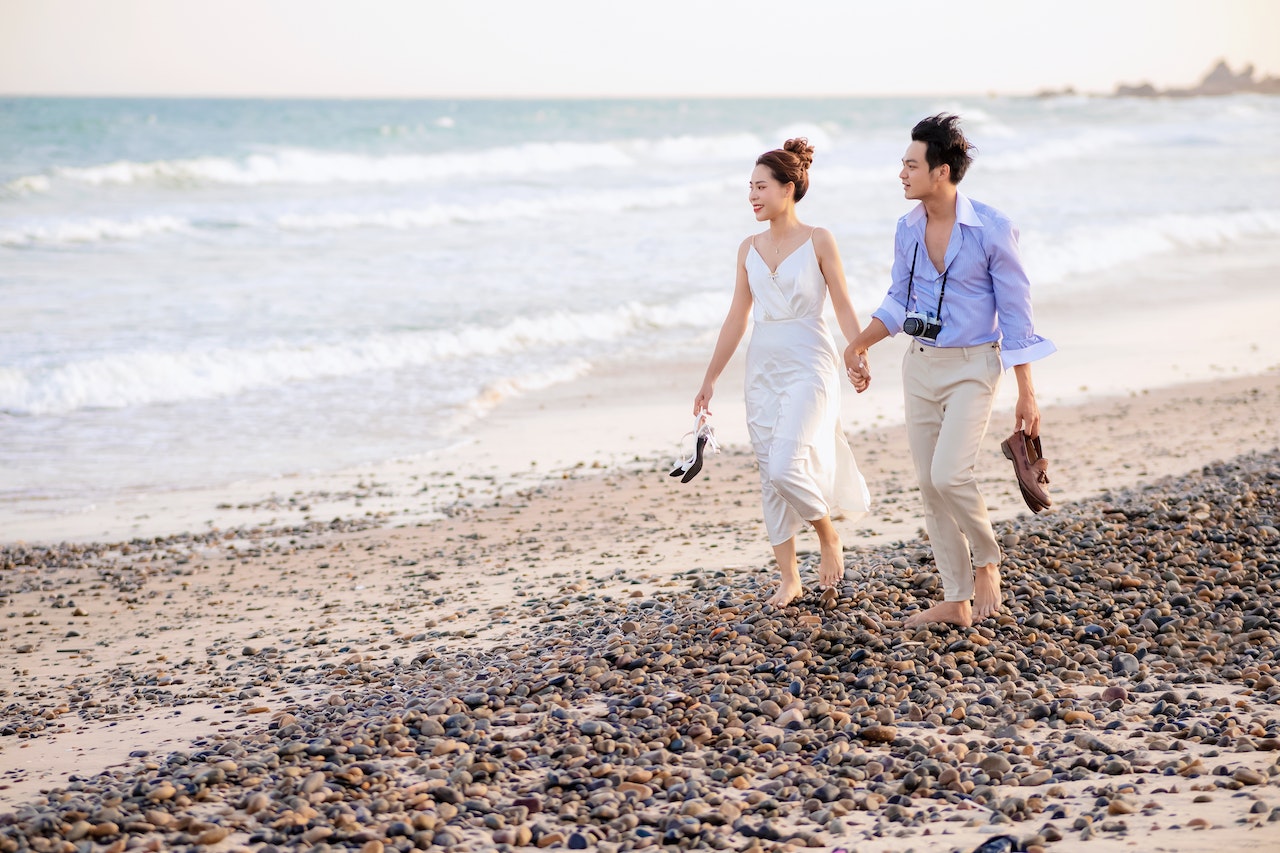 A Couple Walking Holding Hands On A Rocky Beach