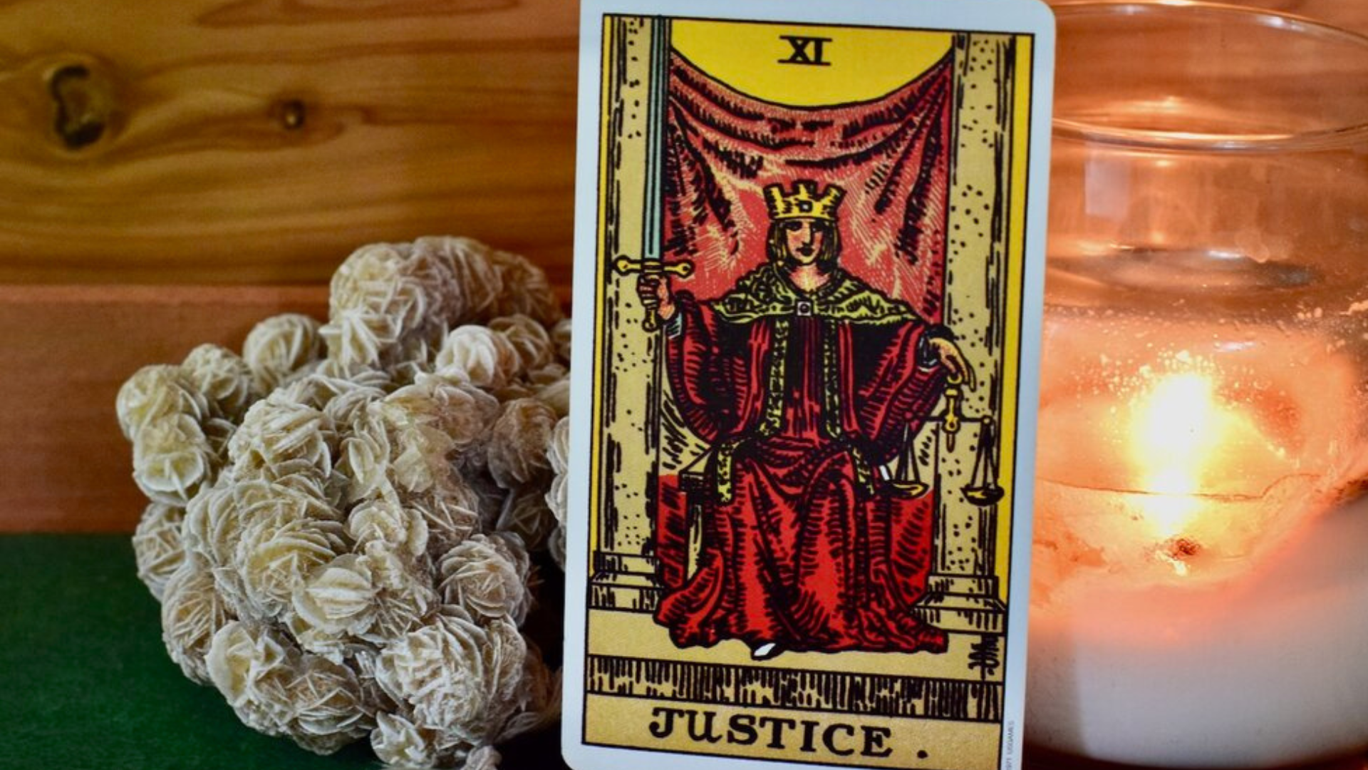 A Justice tarot Card with a plant and candle behind it