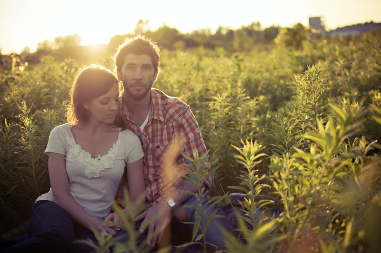 A man and a woman sitting on the ground surrounded by plants