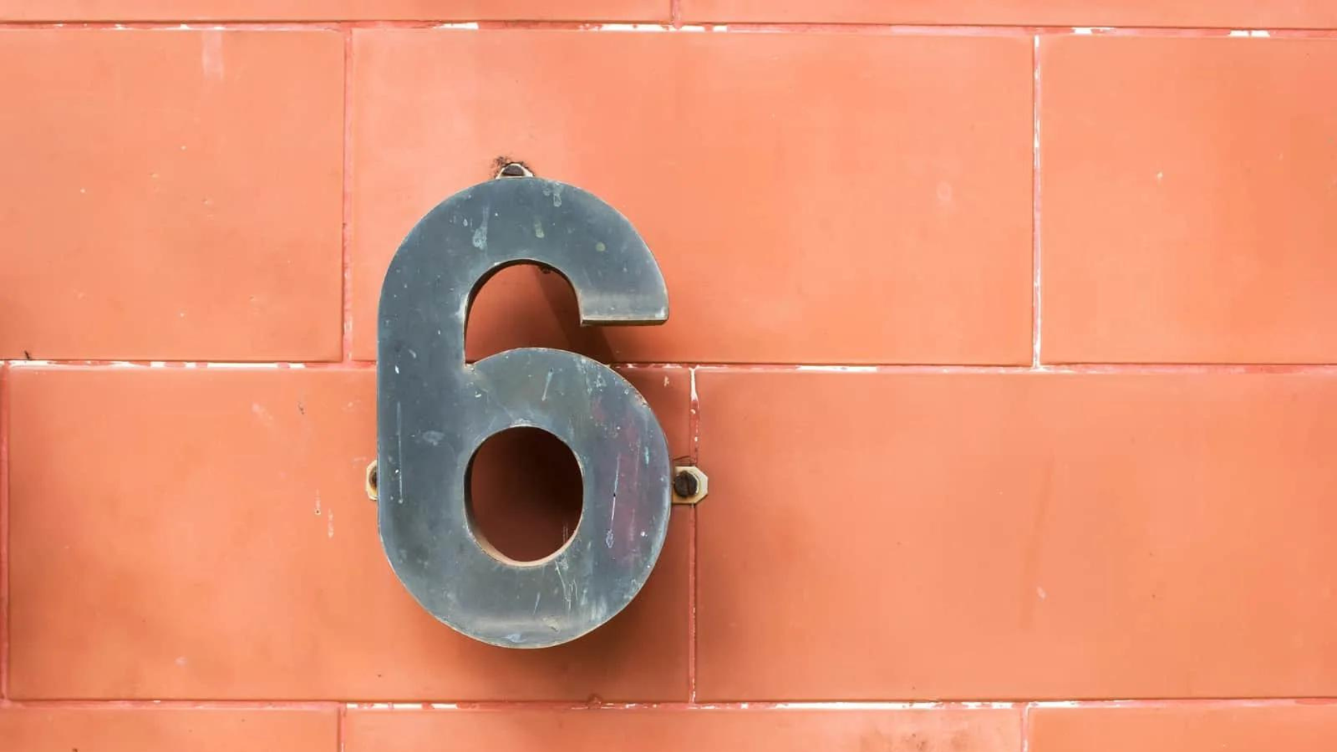 An orange wall with Number 6 made of metal