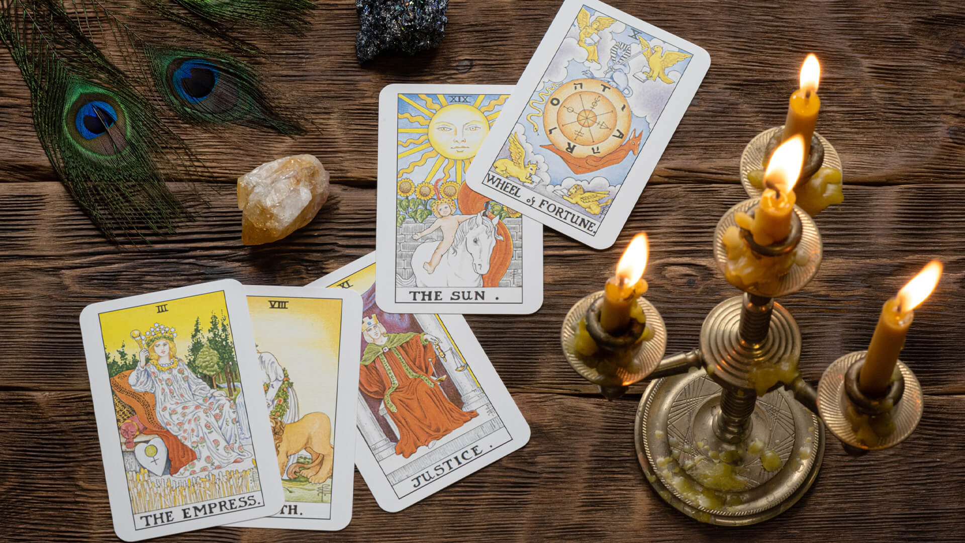 Five tarot cards with a candle placed on a wooden surface