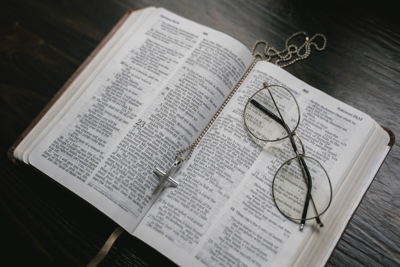 An Open Bible with eyeglasses and a crucifix necklace on it
