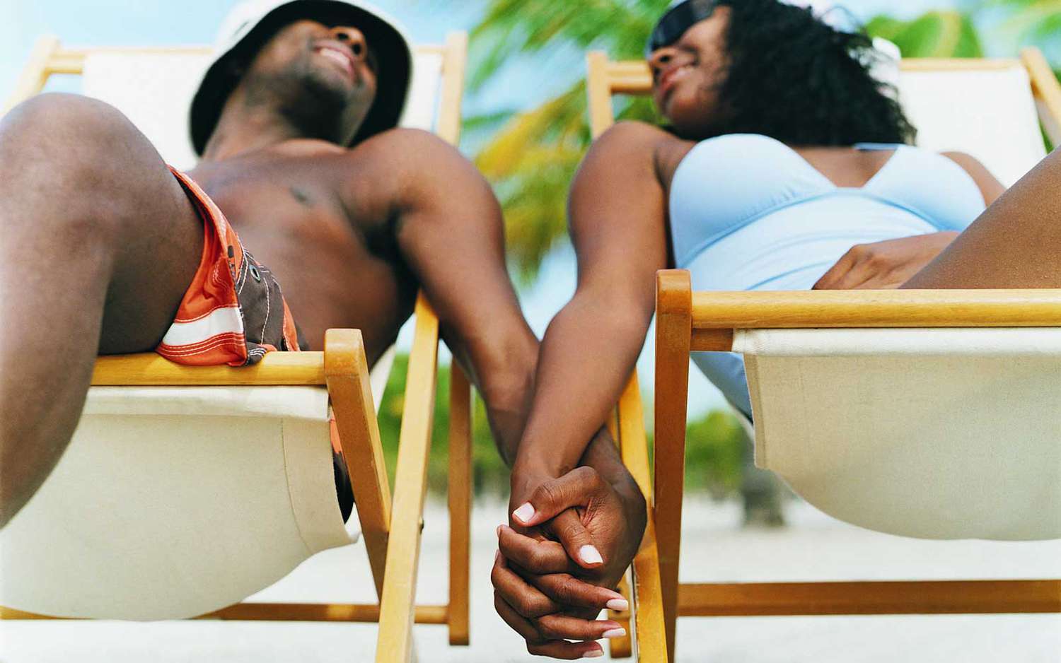 A couple holding hands while sitting on portable folding beach chairs
