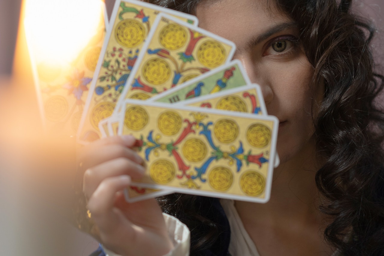 Woman Holding Tarot Cards Over Her Face