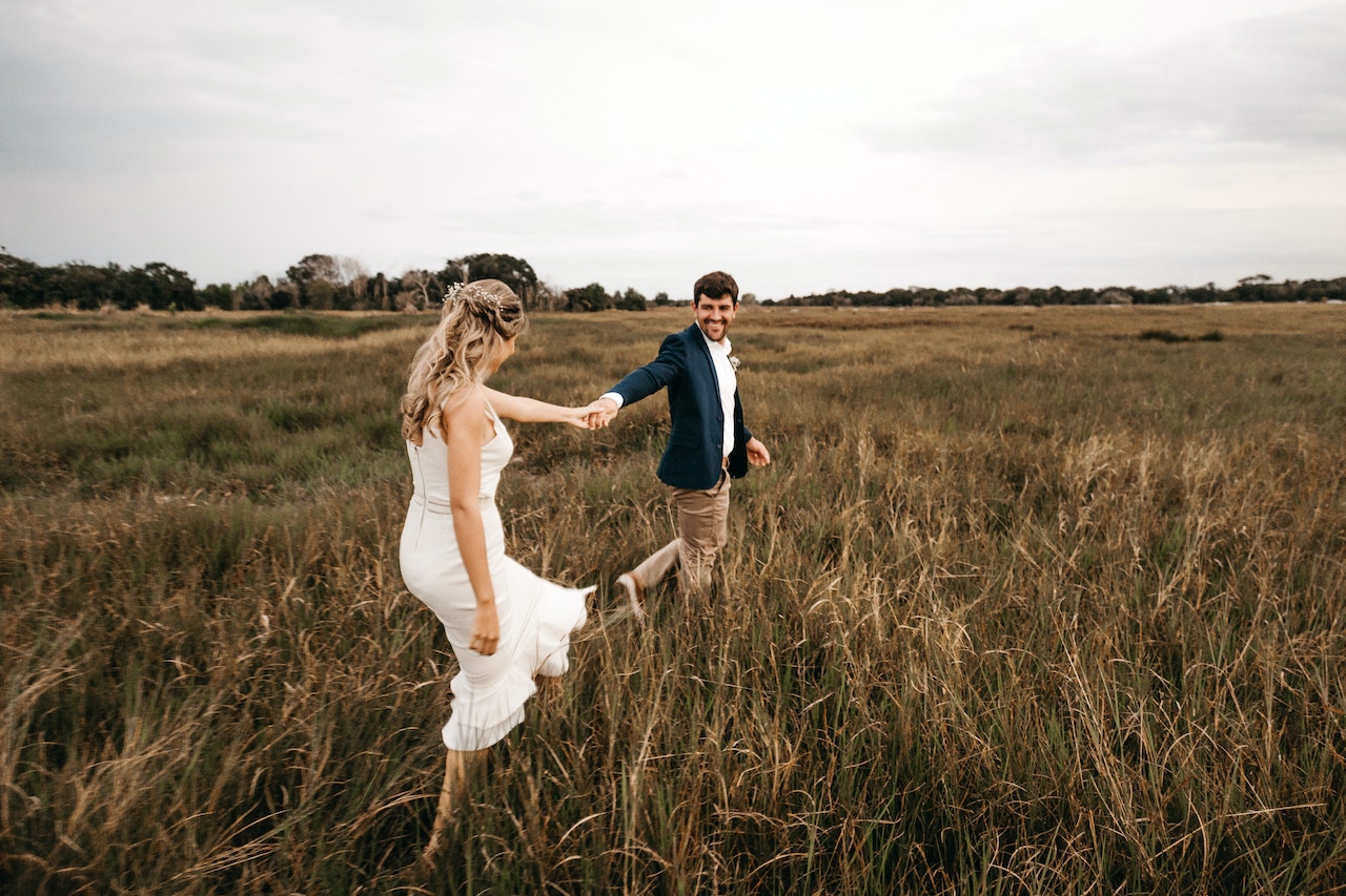 Couple Walking on Grass While Holding Hands