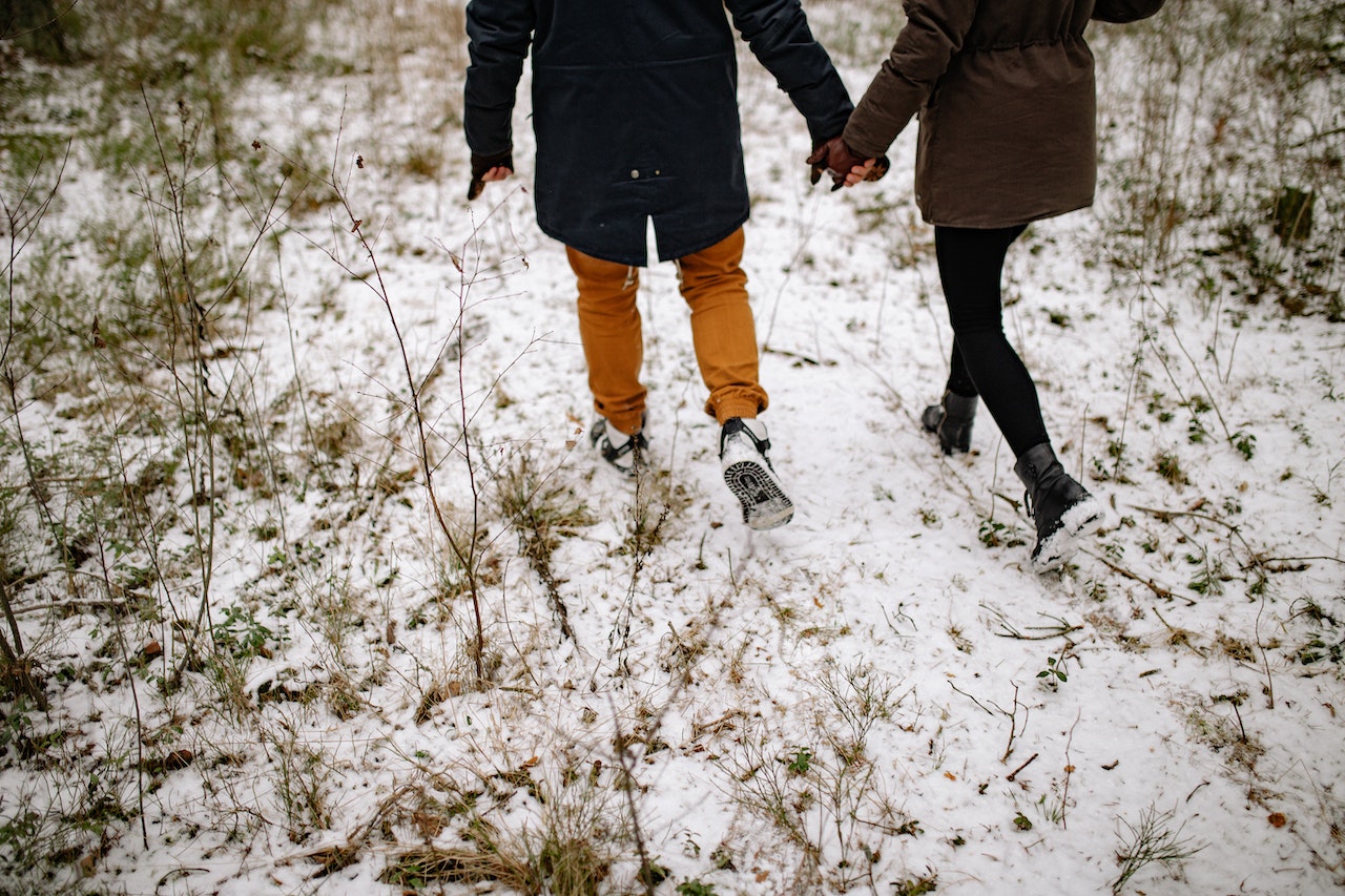 Couple in Outerwear Walking on Winter Ground