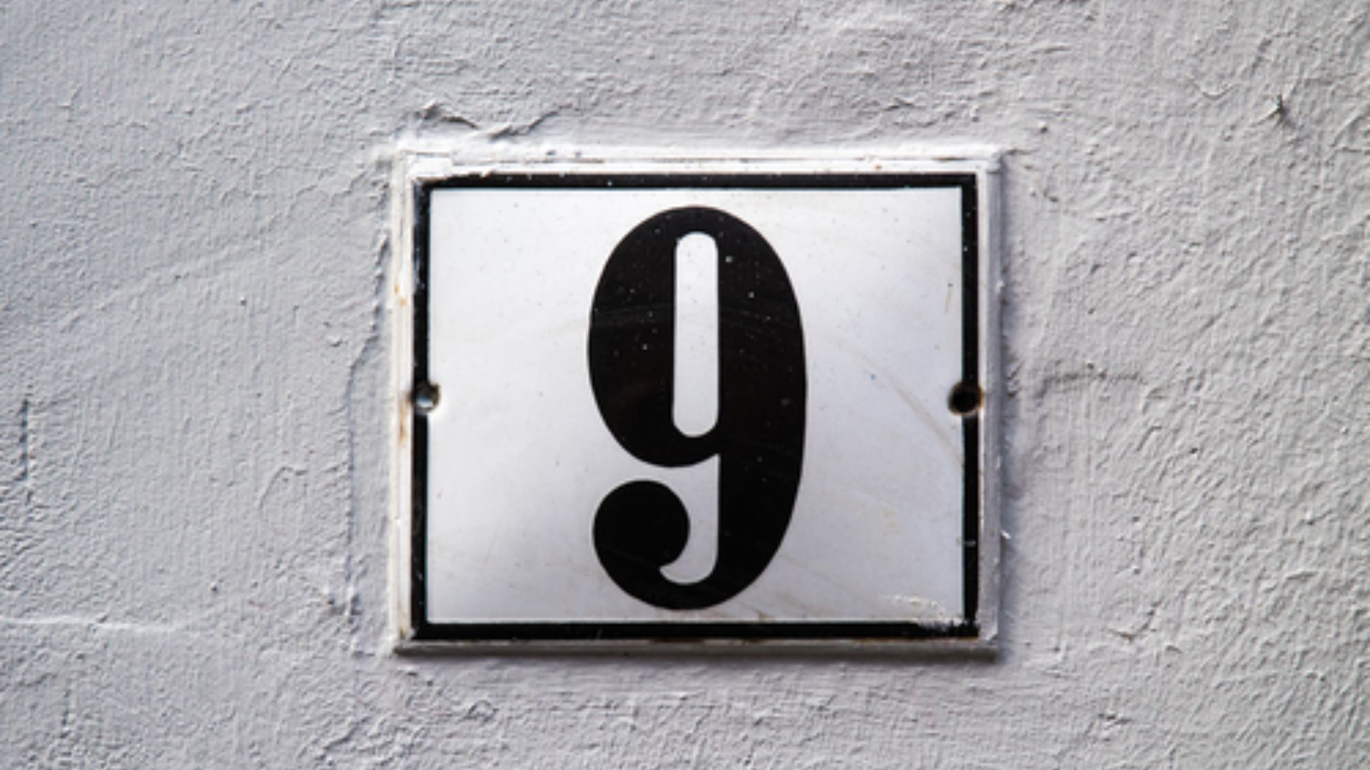 Number 9 On A Metal Plate On A White Wall