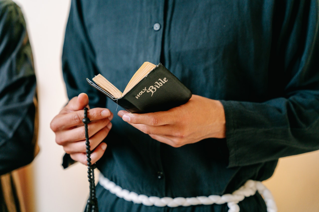 Person reading on Bible and holding a Rosary