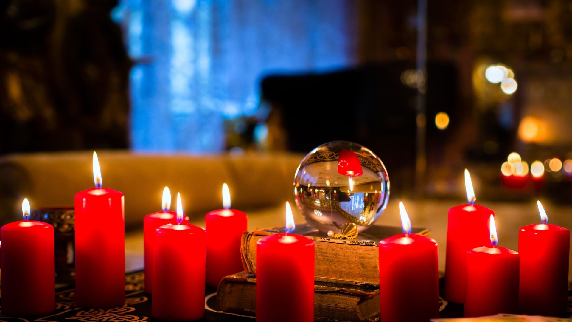 Lit red candles and a crystal ball on top of books