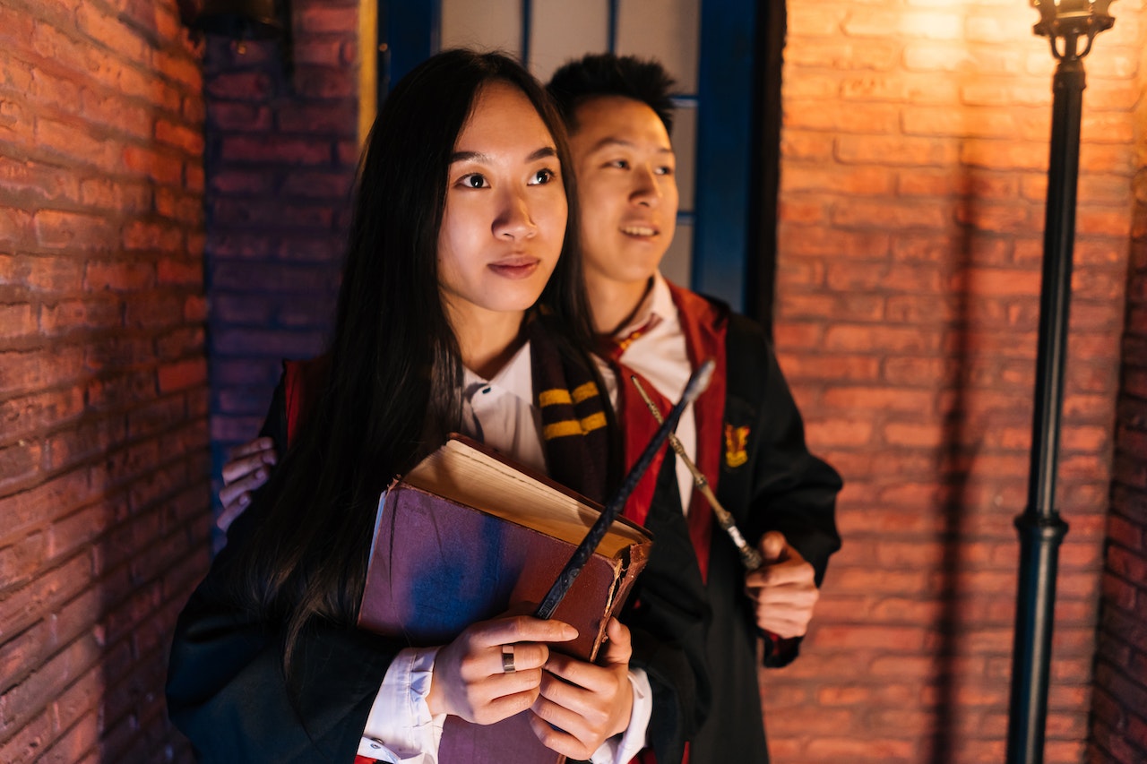 Young Man and Woman in Black wizarding Robes Holding Magic Wands