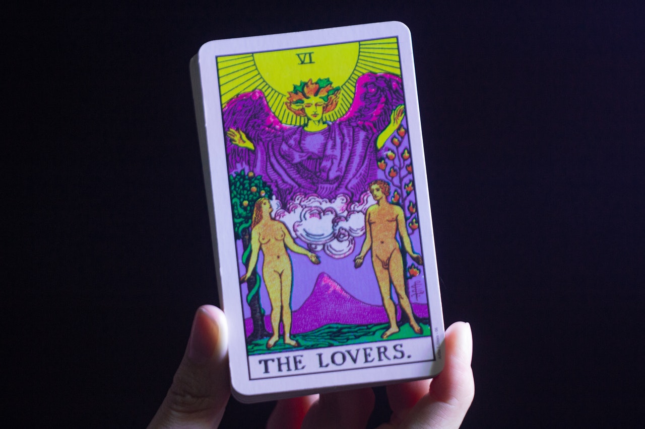 A hand holding The Lovers tarot card