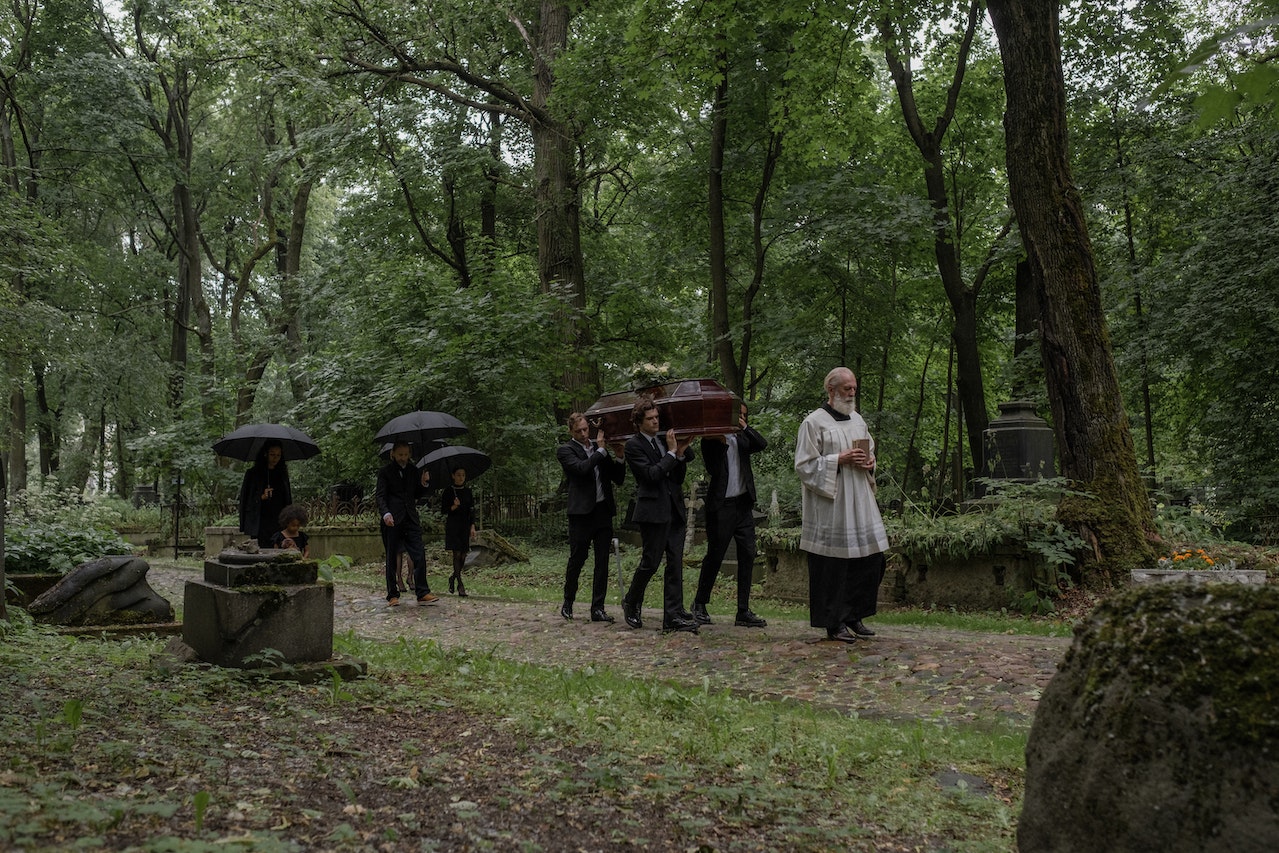 Men in Black Clothes Carrying a Coffin in Cemetery