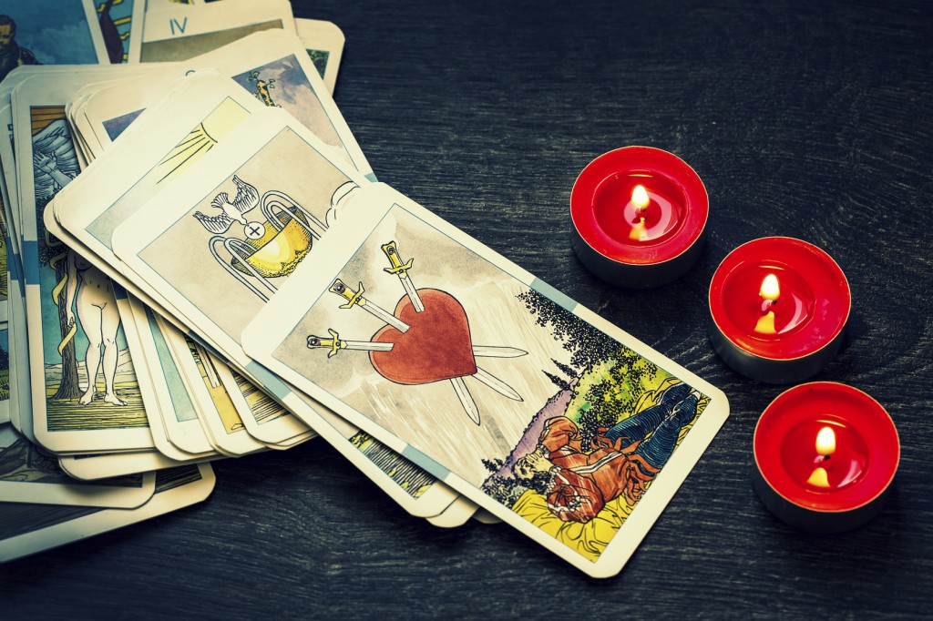 Different tarot cards with three small red candles