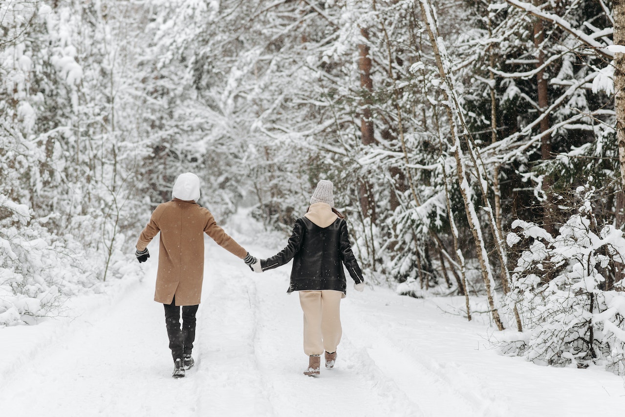 A Couple Holding Hands on a Snow Covered Road