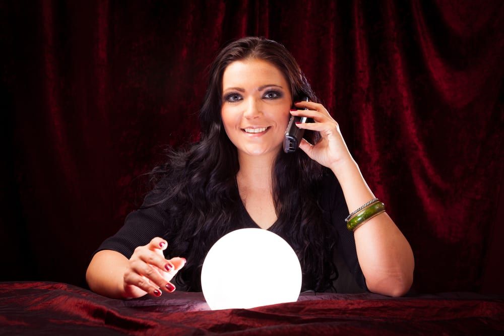 A psychic with a crystal ball while using a phone
