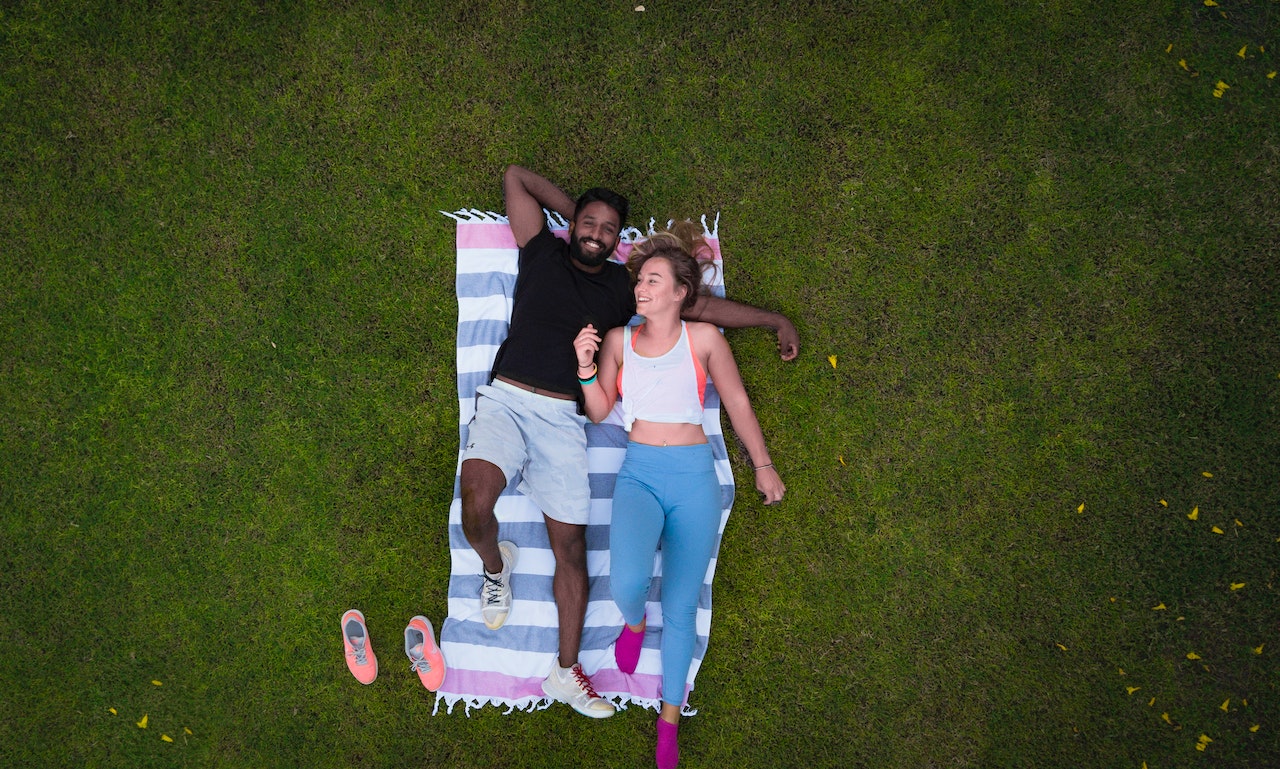 Woman and man lying on a stripe picnic blanket