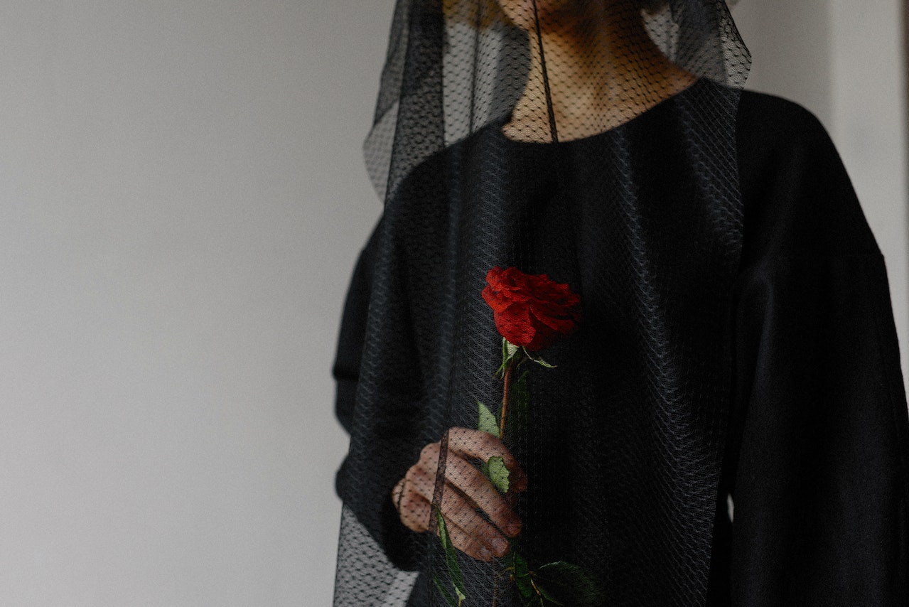 A Person In Black Holding a Red Rose