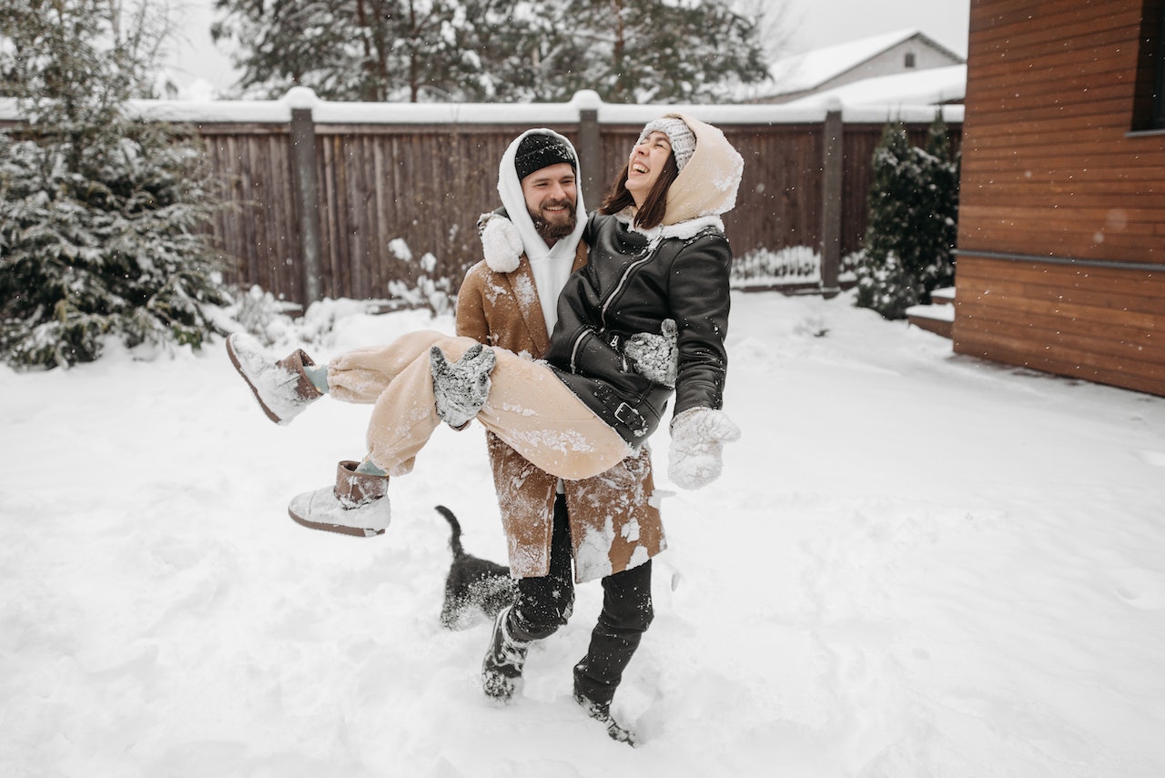Man and Woman Playing on Snow Covered Backyard
