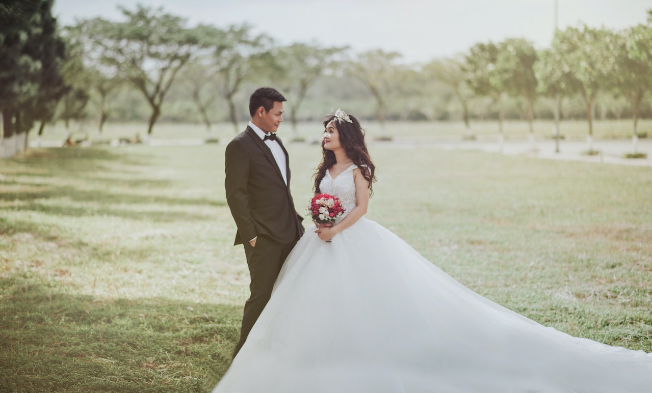 Bride Wearing Wedding Dress and Holding A Bouquet Standing Beside Groom Wearing Tuxedo