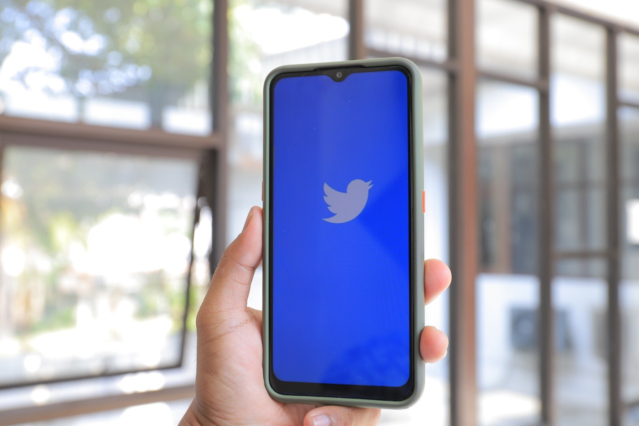 Hand holding a smartphone with a twitter logo on screen
