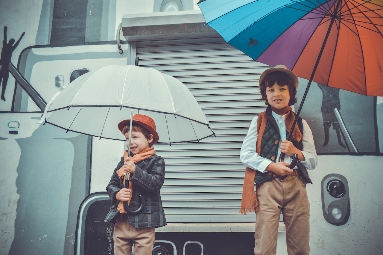 Two Boys Holding Umbrellas While Smiling
