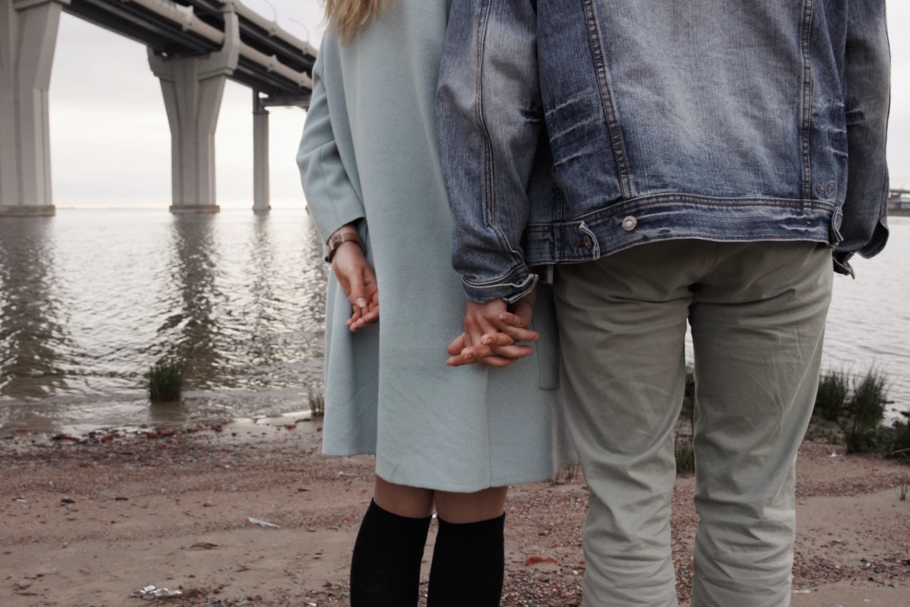 Man And Woman Holding Hands Near Body Of Water