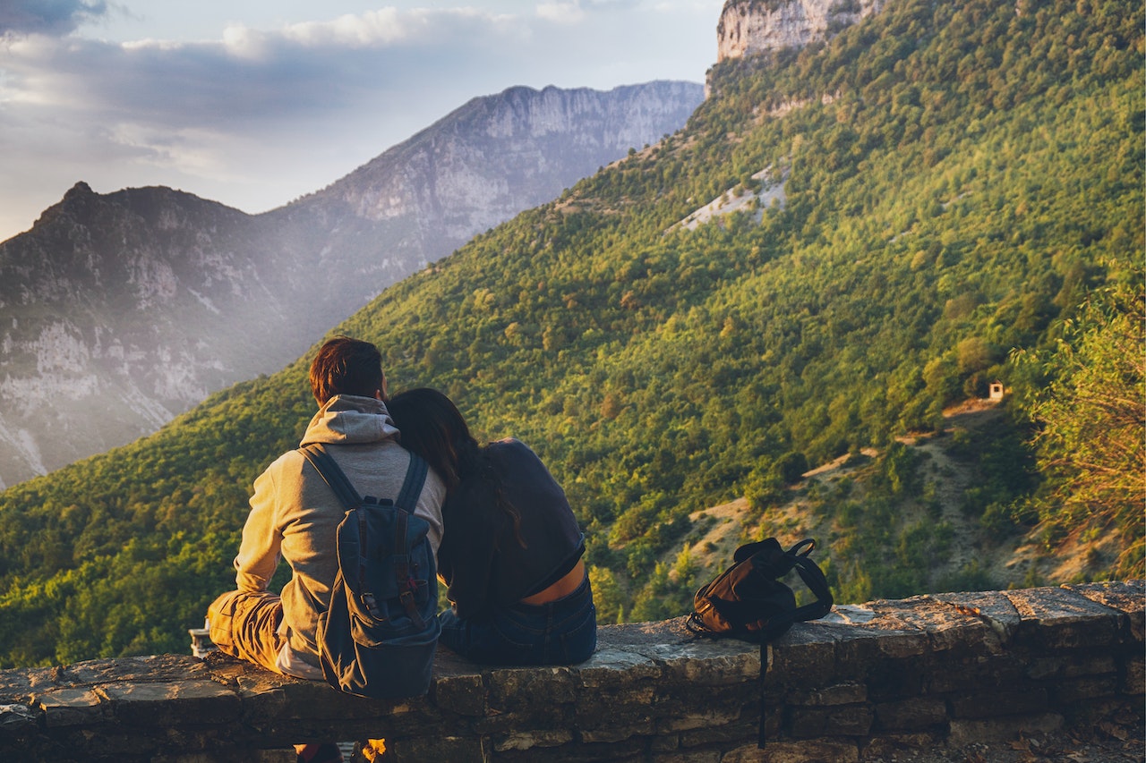 A Couple Sitting Together While Facing A View Of The Mountain