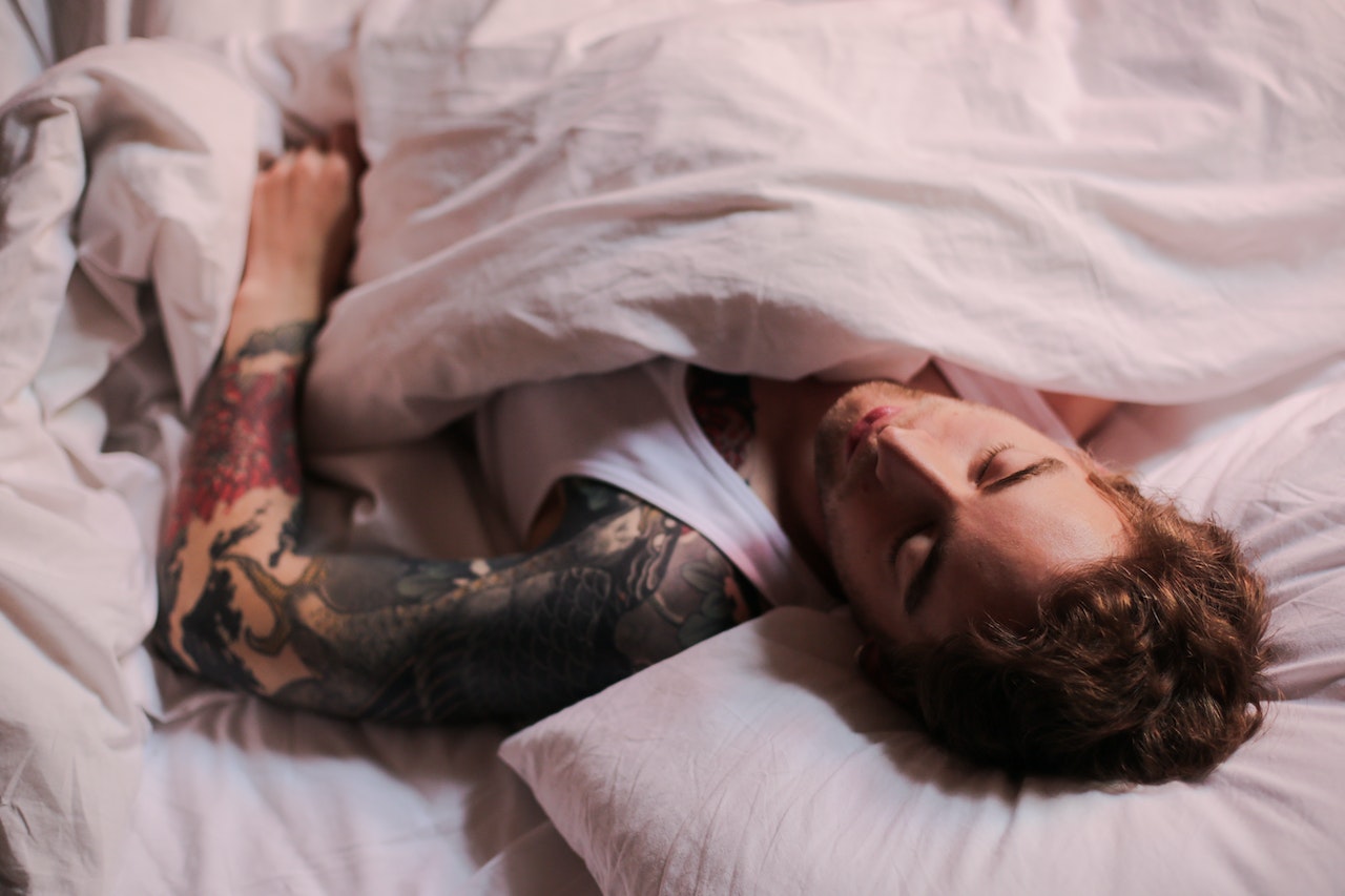 Man Lying on Bed With Tattoo on Her Body