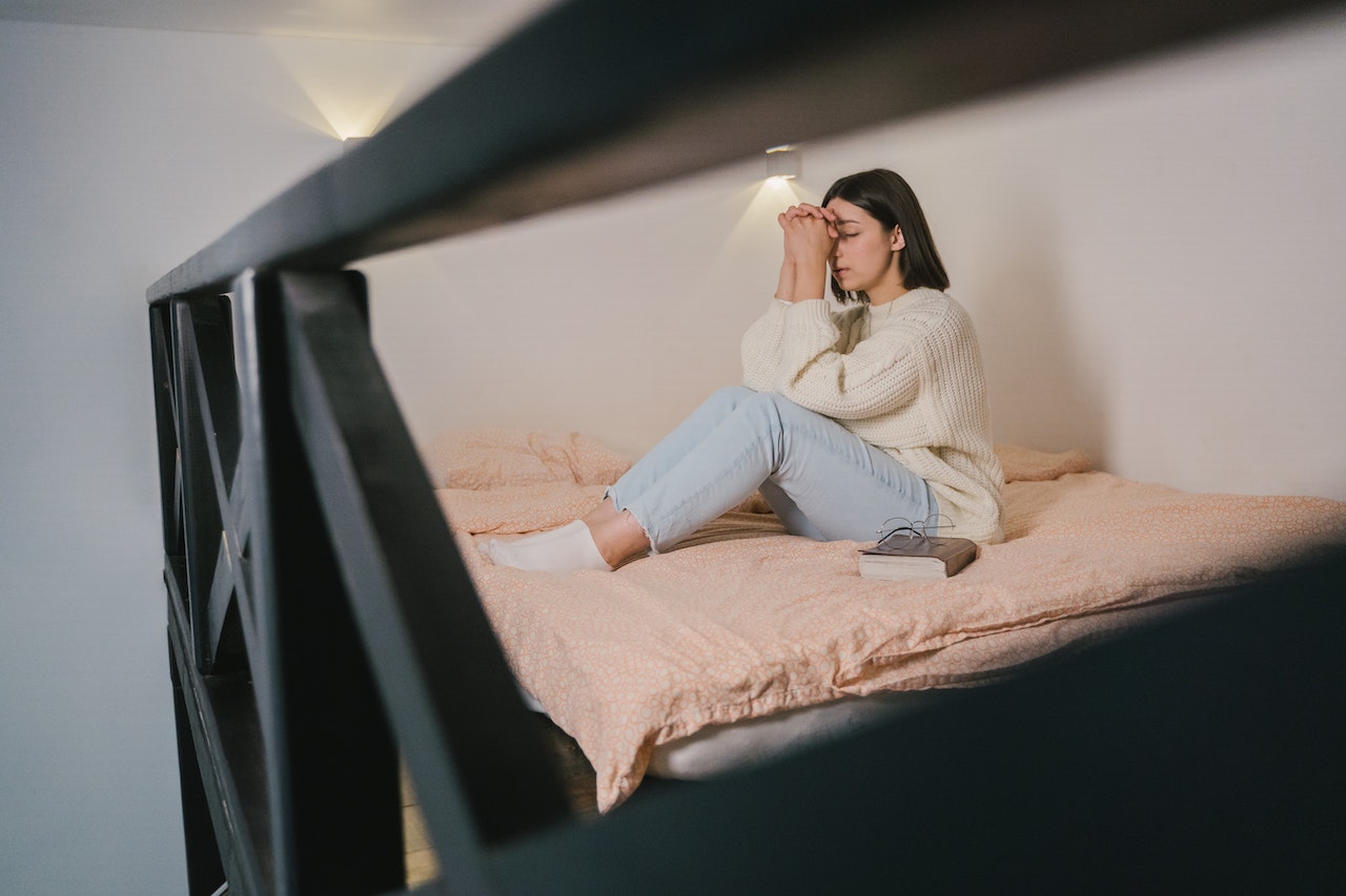 Woman in White Sweater and Blue Denim Jeans Sitting on Bed